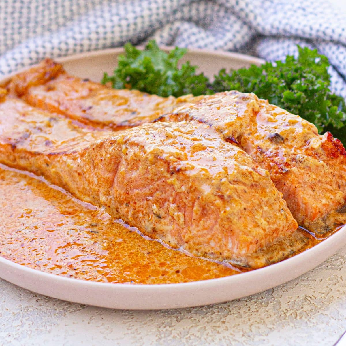 Two salmon filets in cream sauce on a plate.