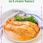 Two salmon filets in cream sauce on a plate.
