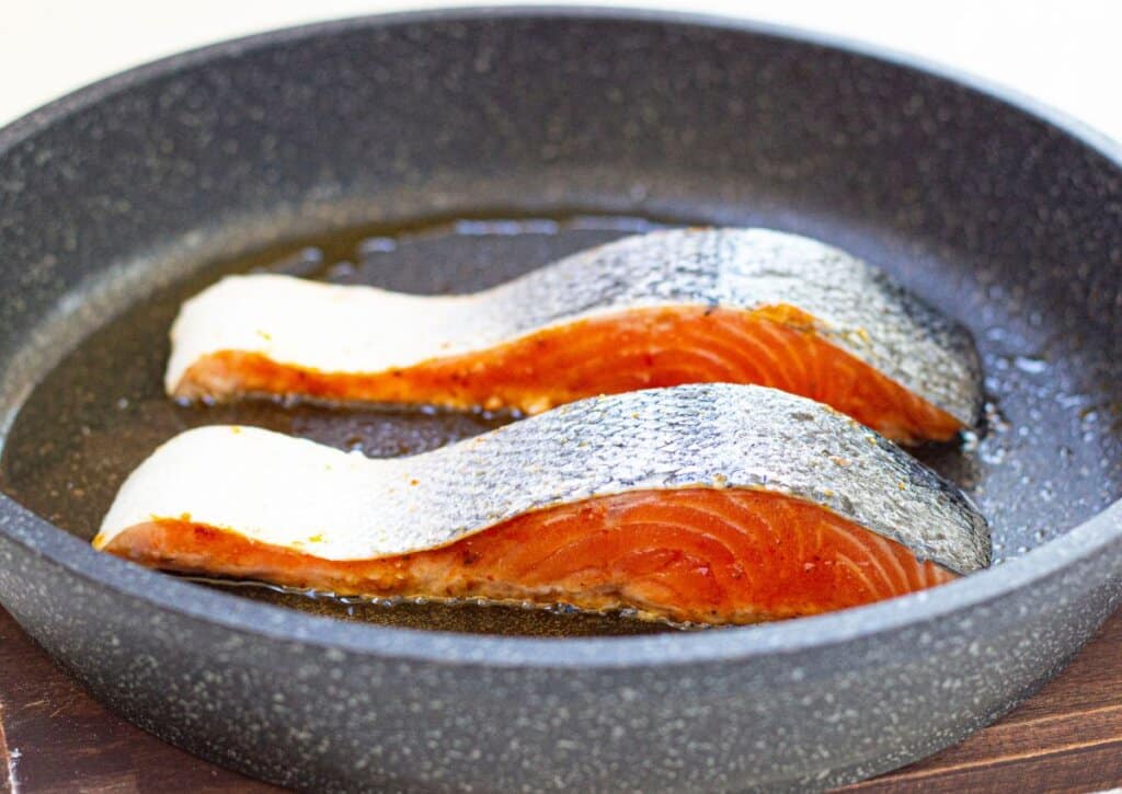 Skin side up fish in a skillet.