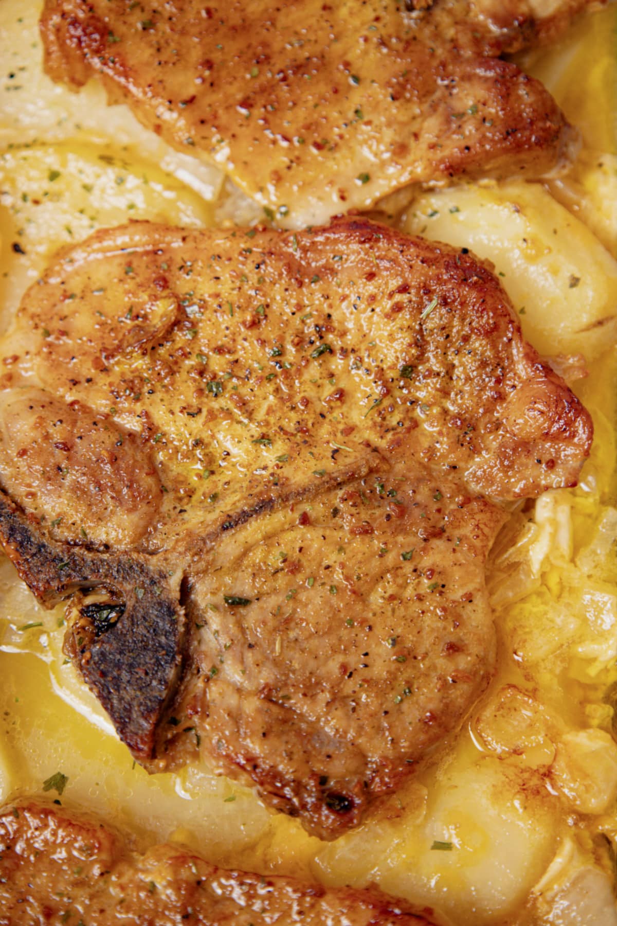 Pork chop on top of a bed of scalloped potatoes.