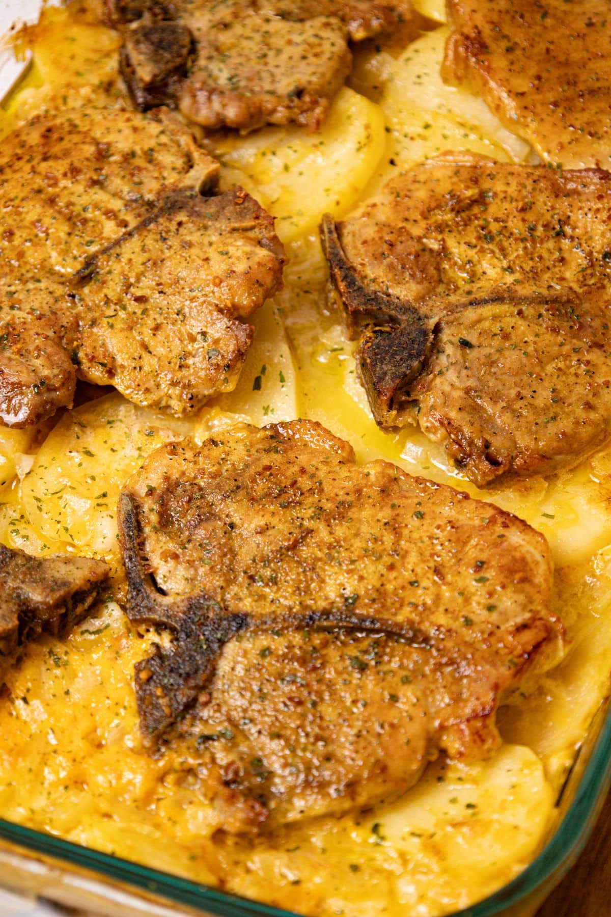 Pork chop on top of a bed of scalloped potatoes.