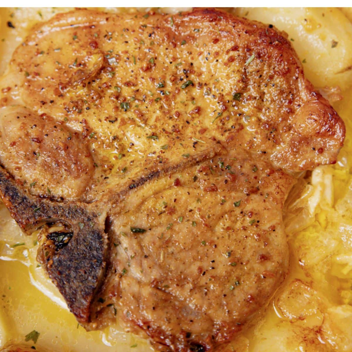 Pork chop on top of a bed of scalloped potatoes.
