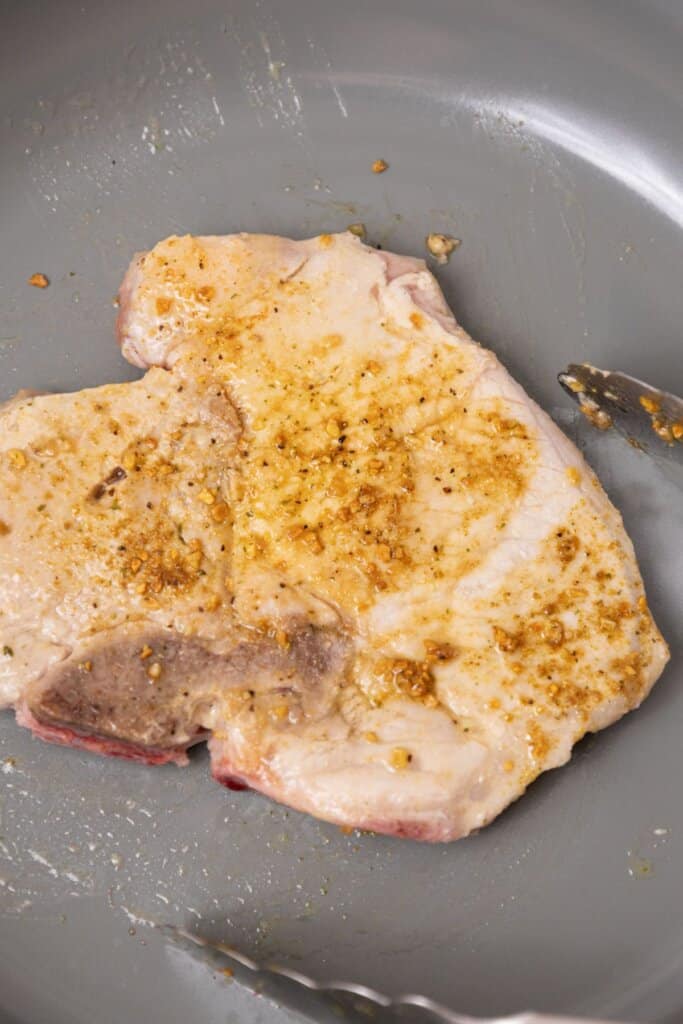 Meat being seared in a skillet.