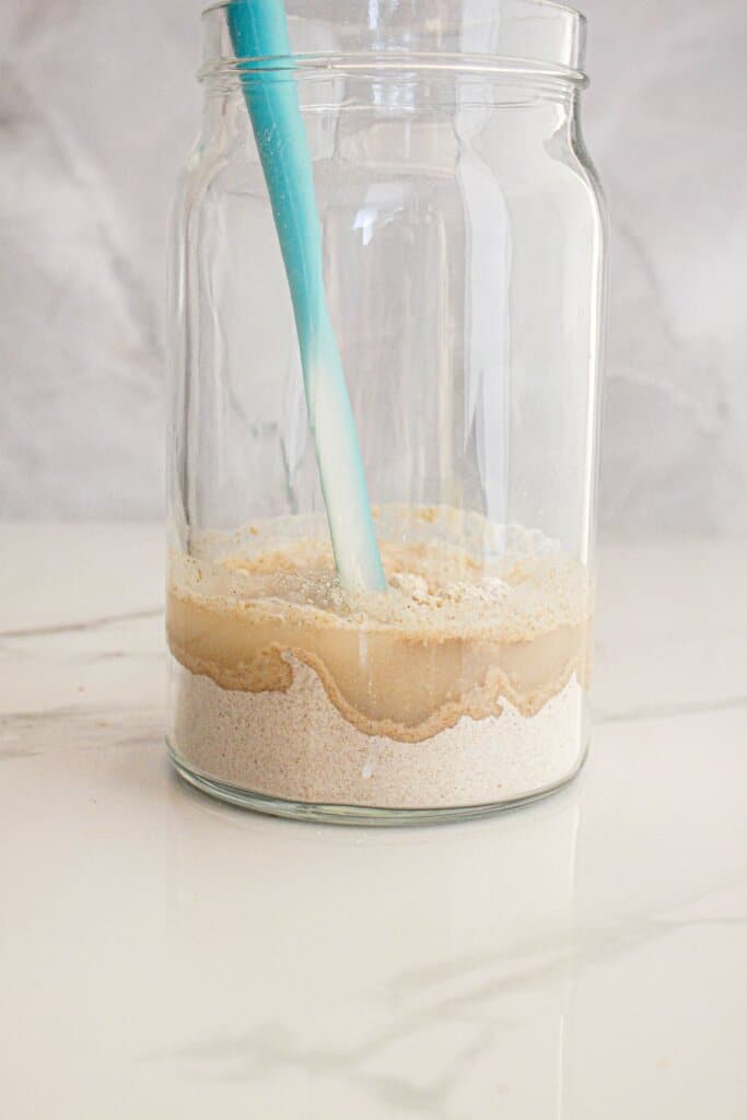 Flour and water being mixed in a jar.