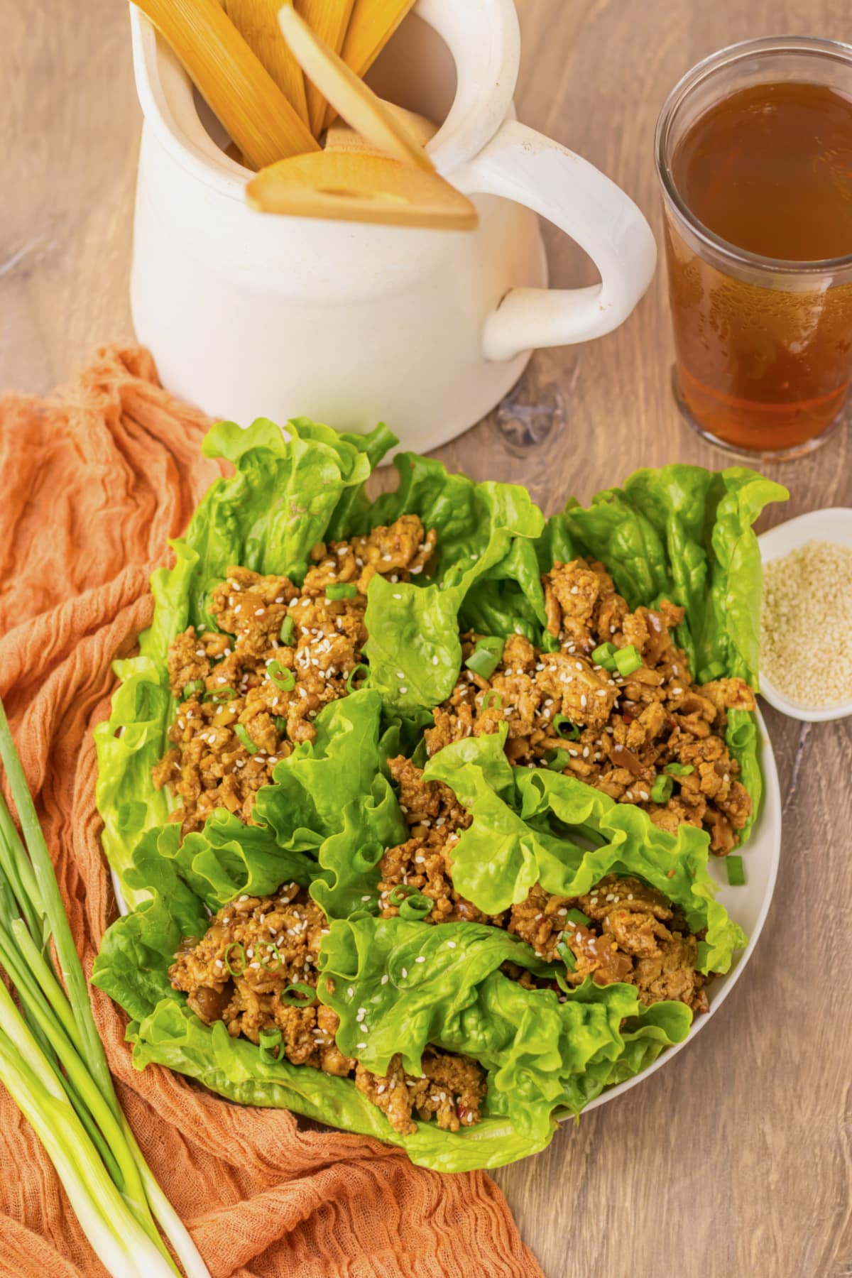 Lettuce cups filled with chicken on a white plate.
