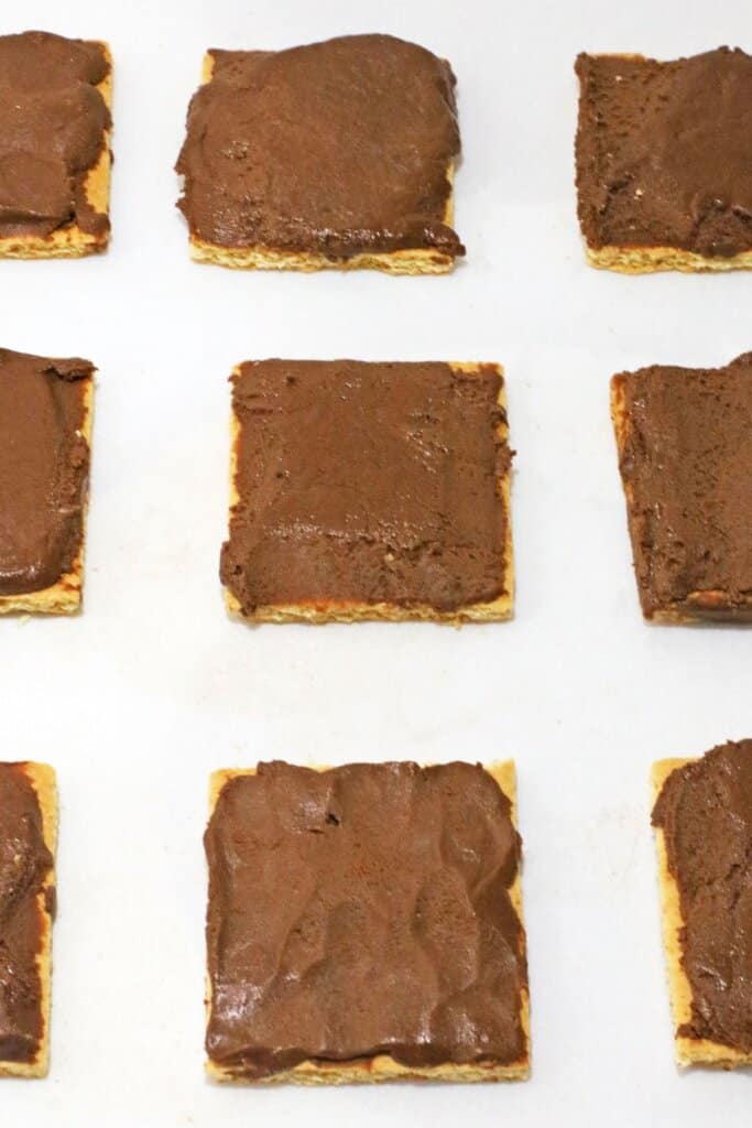 Melted chocolate being spread on graham crackers.