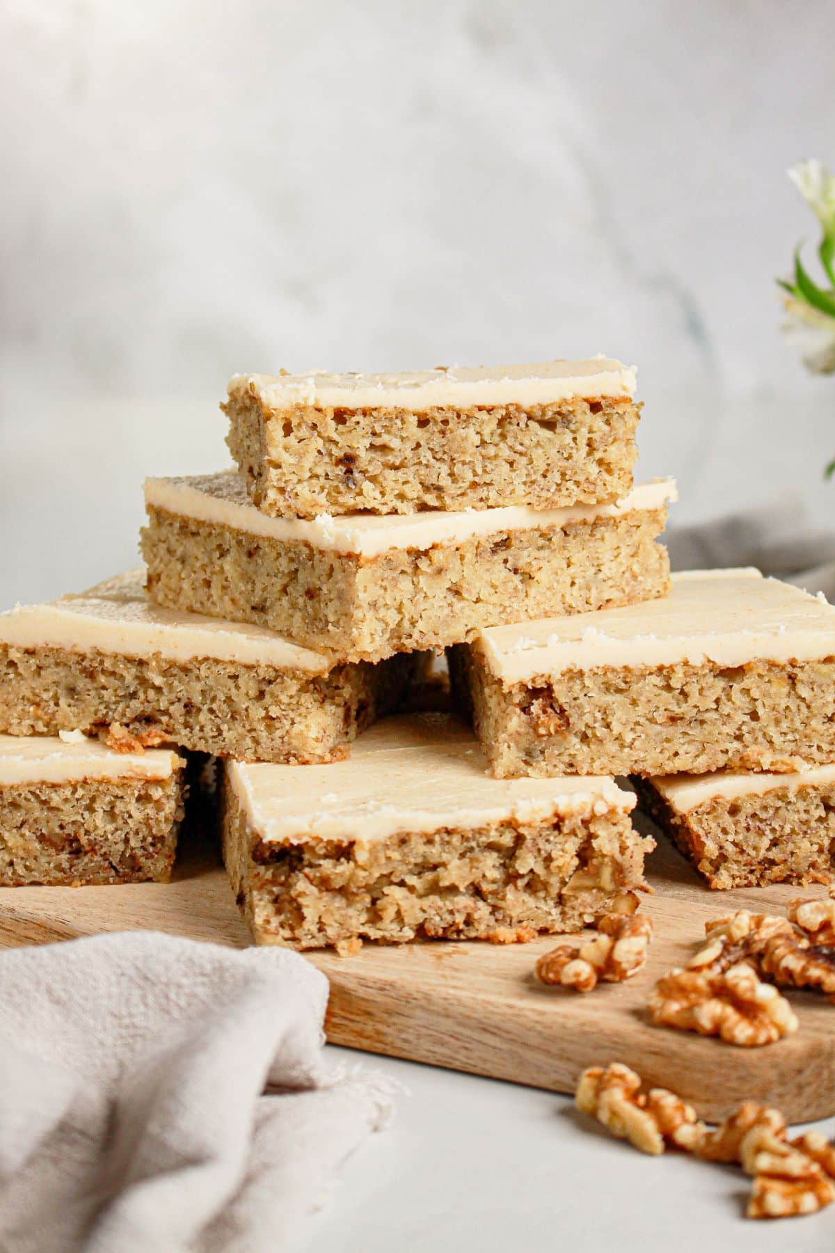 Banana bread brownies stacked in a pyramid on a cutting board.