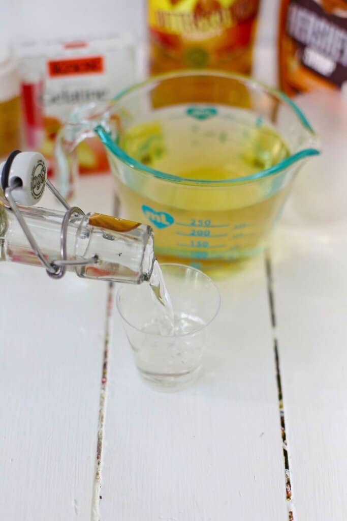 Clear liquid being poured into a small cup.