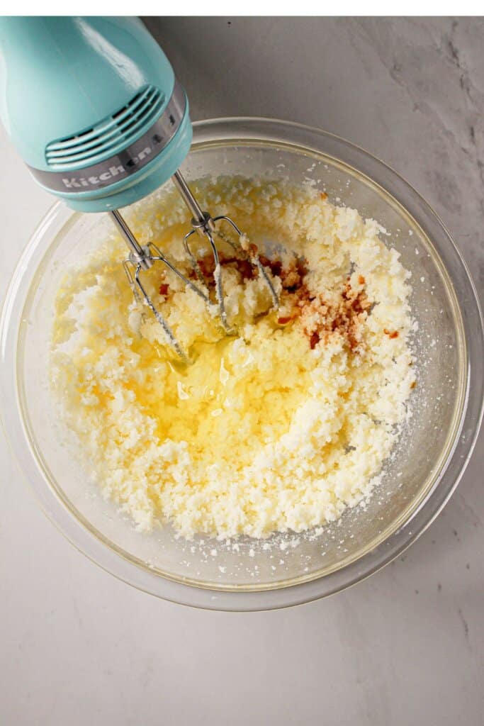 Butter, sugar, and vanilla being creamed together in a glass bowl.
