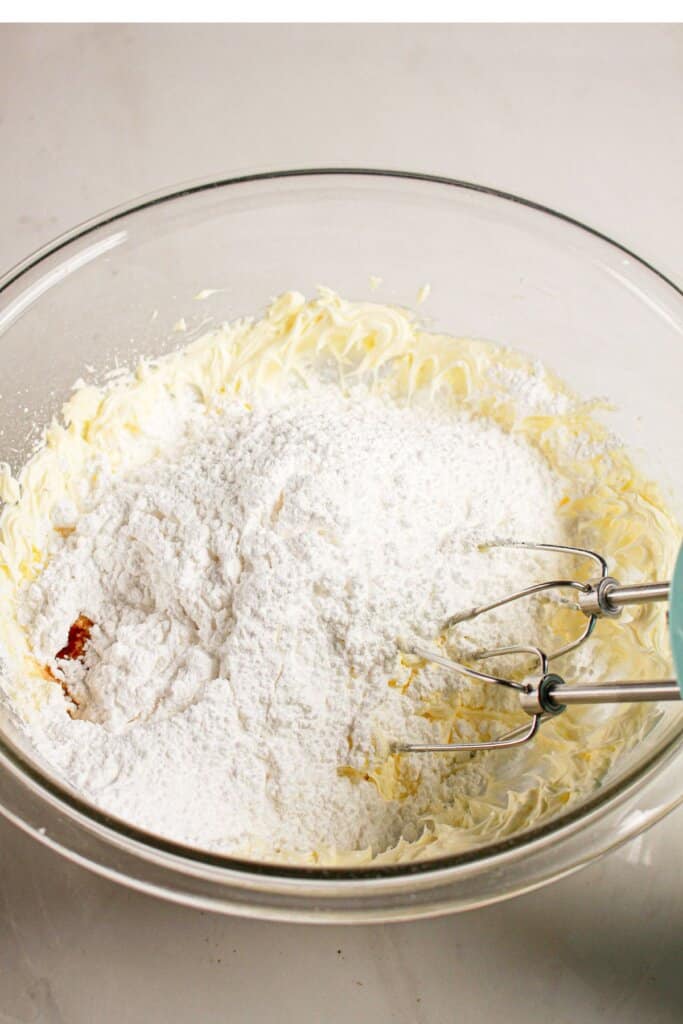 Frosting being mixed in a glass bowl.