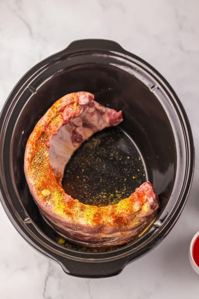 Ribs and seasonings in a crock pot.