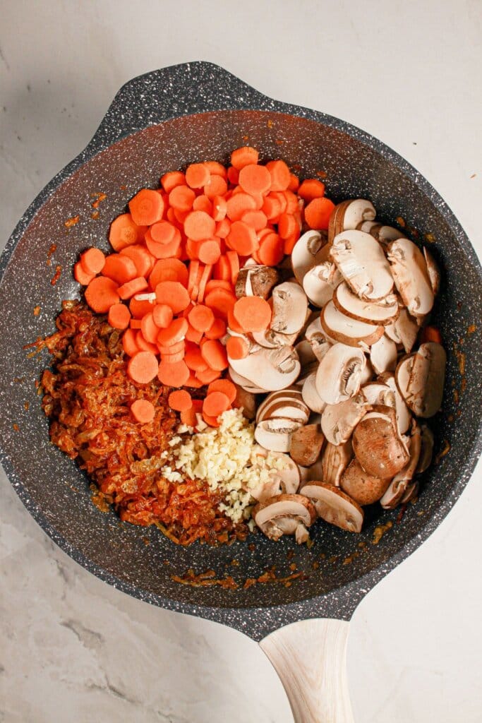 Carrots, mushrooms, and onions in a skillet.