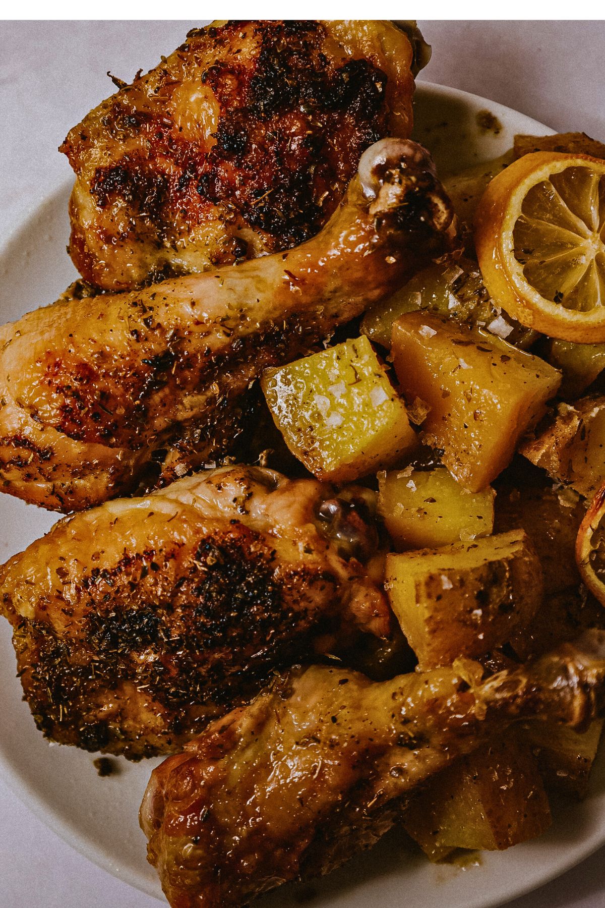 Chicken pieces and potatoes on a white plate.