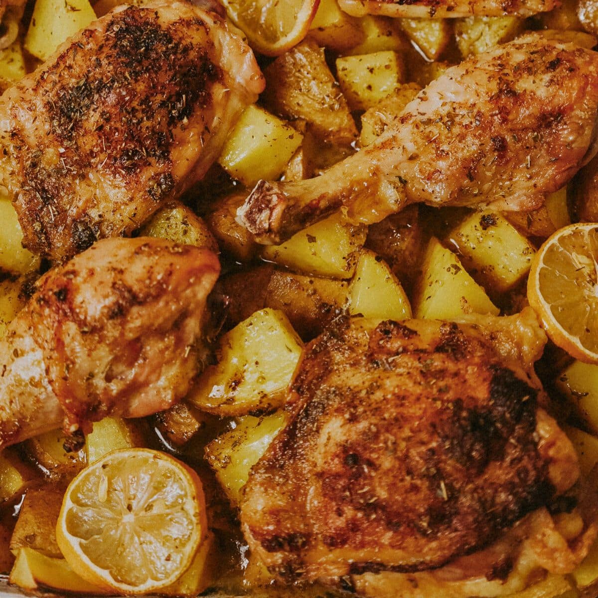 Glass baking dish full of chicken pieces and potatoes.