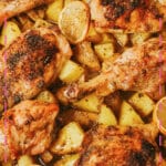 Glass baking dish full of chicken pieces and potatoes.