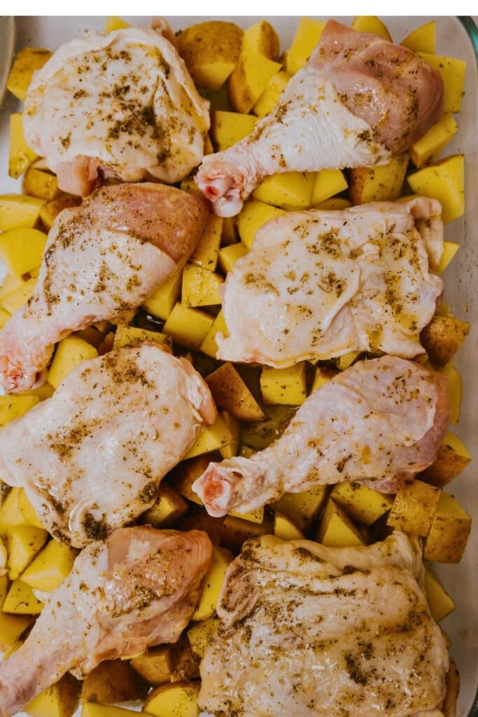 Meat being placed on top of vegetables in a baking dish.