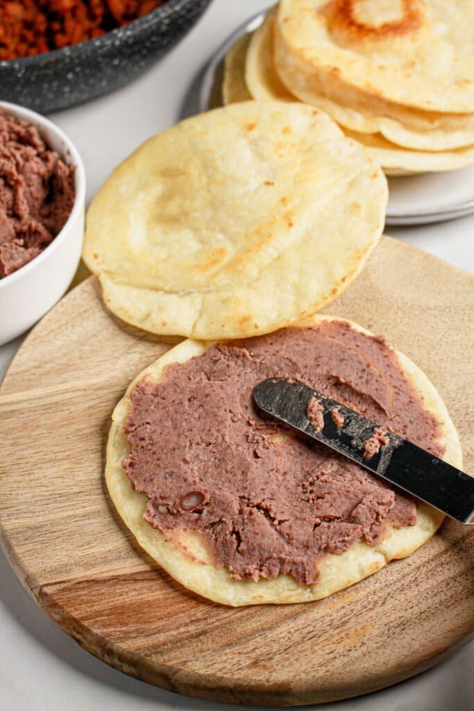 Beans being spread on a tortilla.