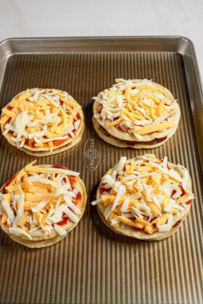 Tortillas and cheese on a metal baking dish.