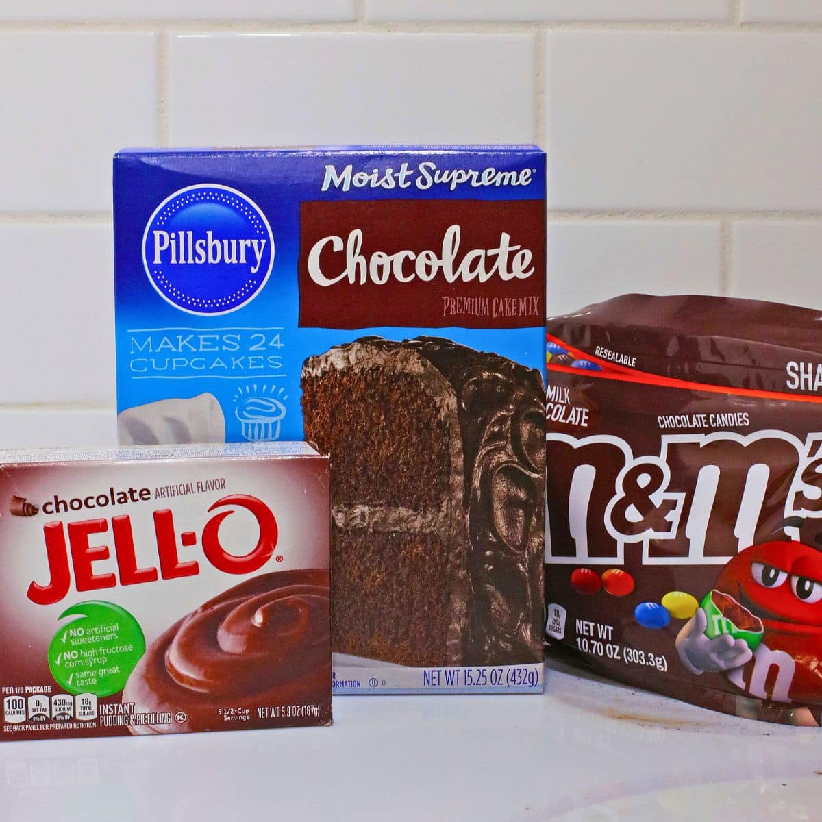 Box of cake mix, pudding, and bag of M&M's on the counter.