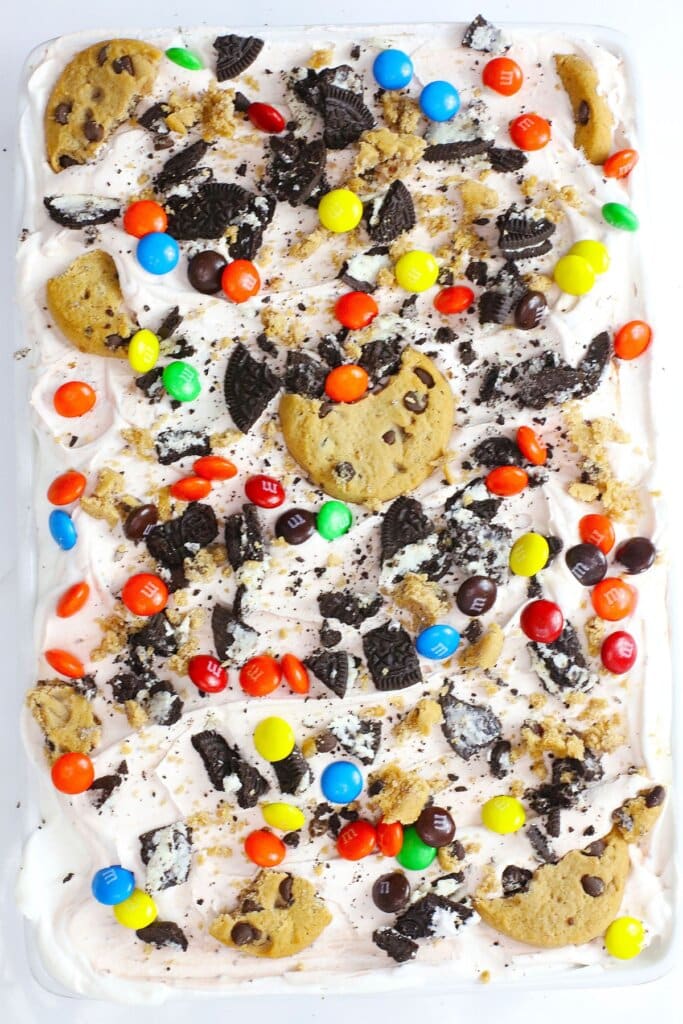 Candy and cookies being sprinkled on top of dessert.