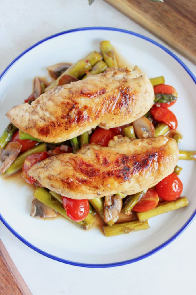 Chicken tenderloins on top of a bed of vegetables.