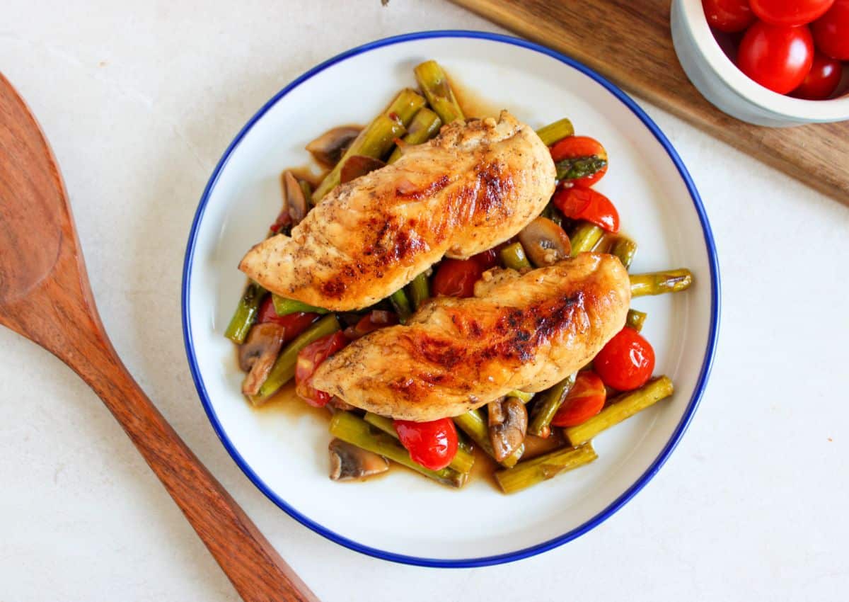 Chicken tenderloins on top of a bed of vegetables.