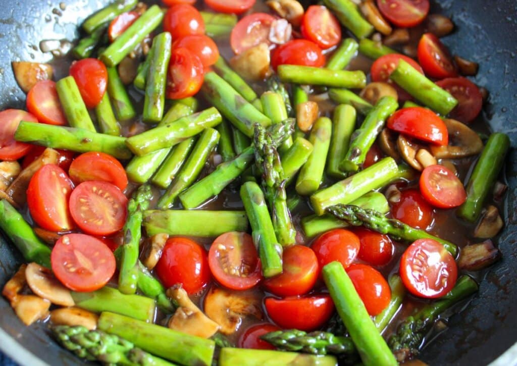 Skillet full of vegetables and sauce.