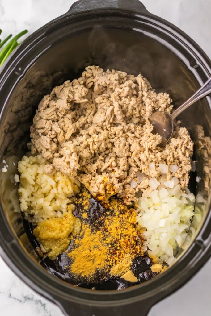 Ingredients being added to a slow cooker ready to cook.