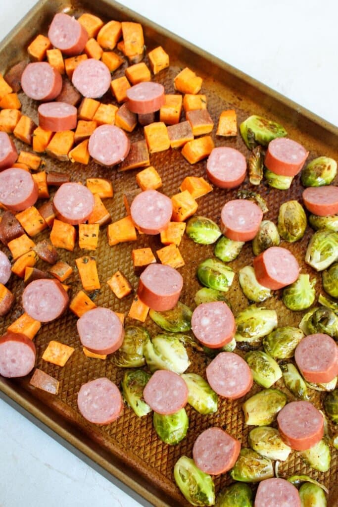 Sausage being added to baking sheet.
