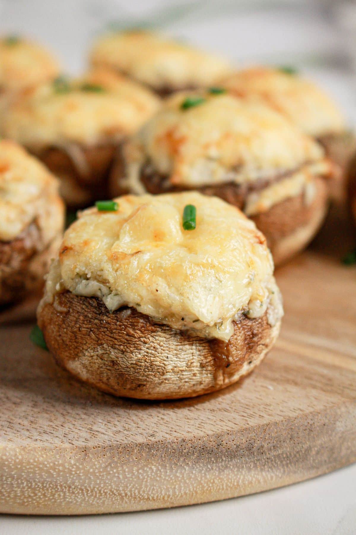 Cream cheese stuffed mushrooms on a wooden cutting board.