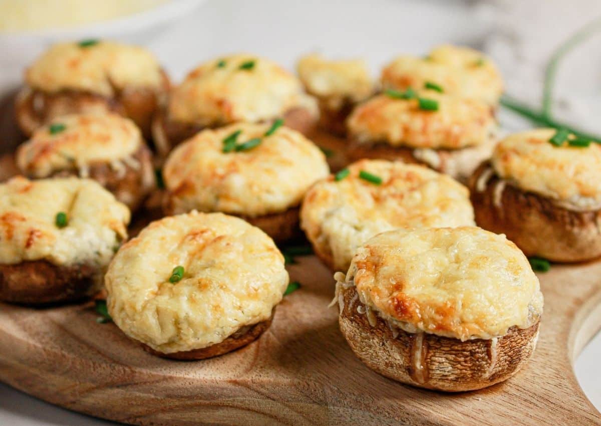 Cream cheese stuffed mushrooms on a wooden cutting board.