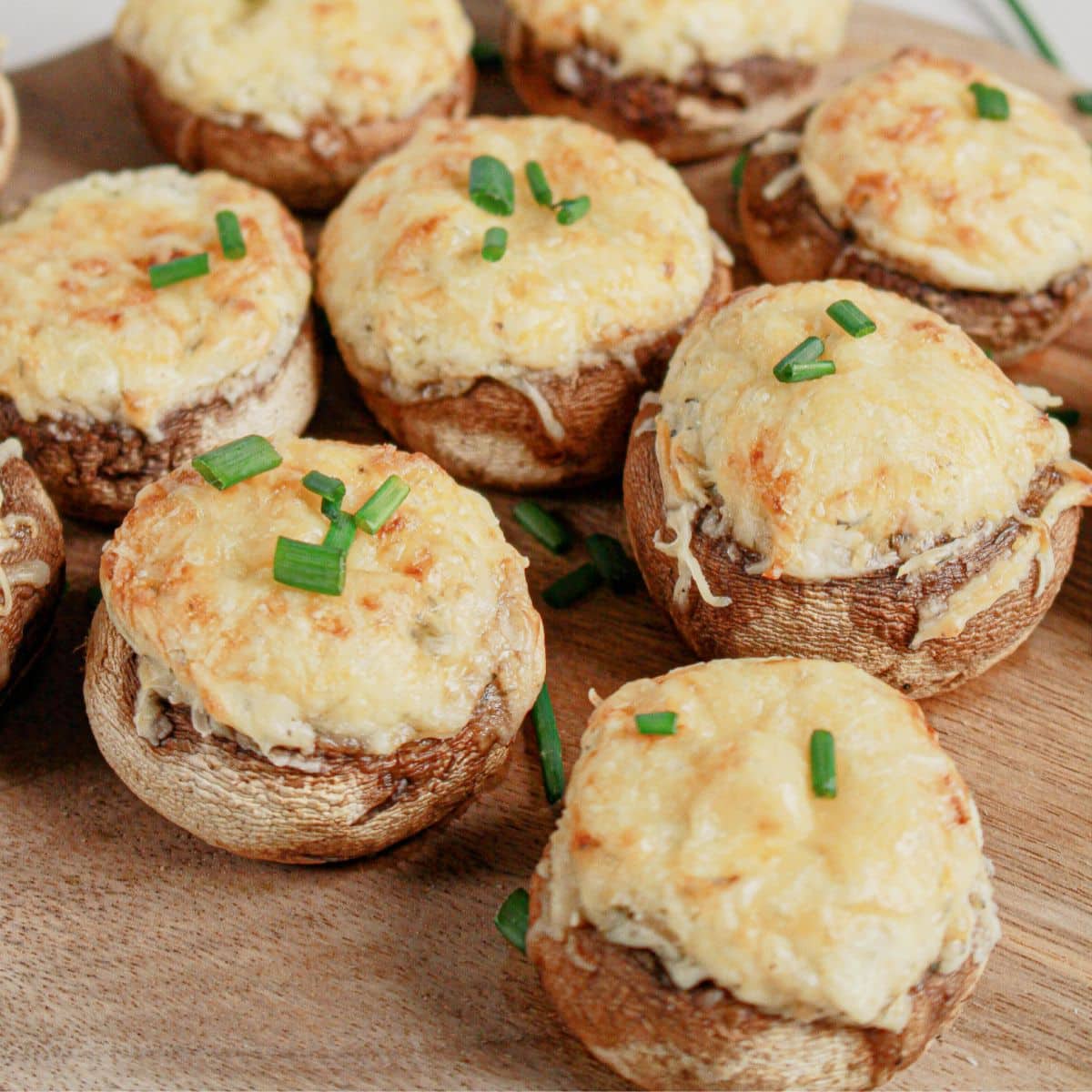 Cream cheese stuffed mushrooms on a wooden cutting board.