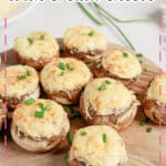 Cream cheese stuffed mushrooms on a wooden cutting board.