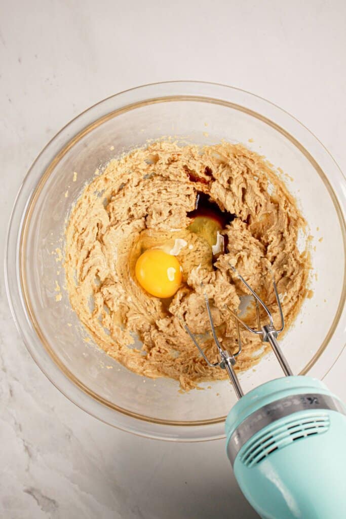 Eggs being added to batter in a glass bowl.