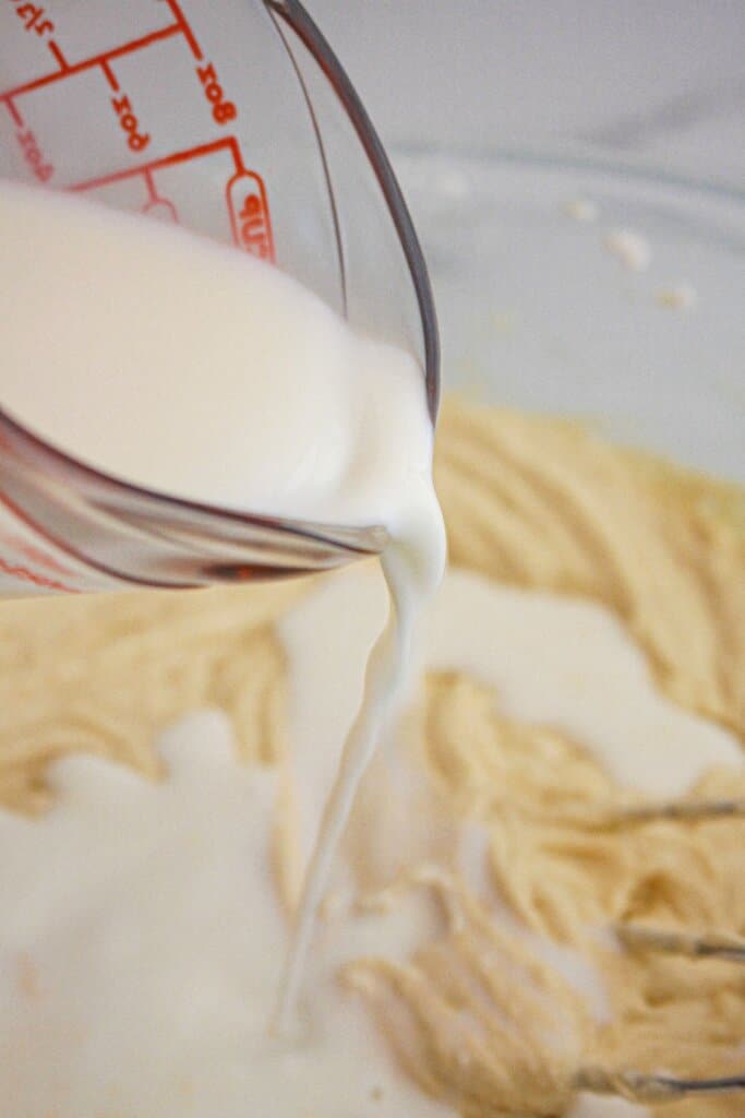 Milk being added to batter in a glass bowl.