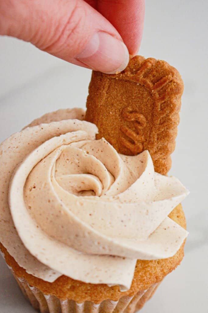Cookie being placed on top of a cupcake.