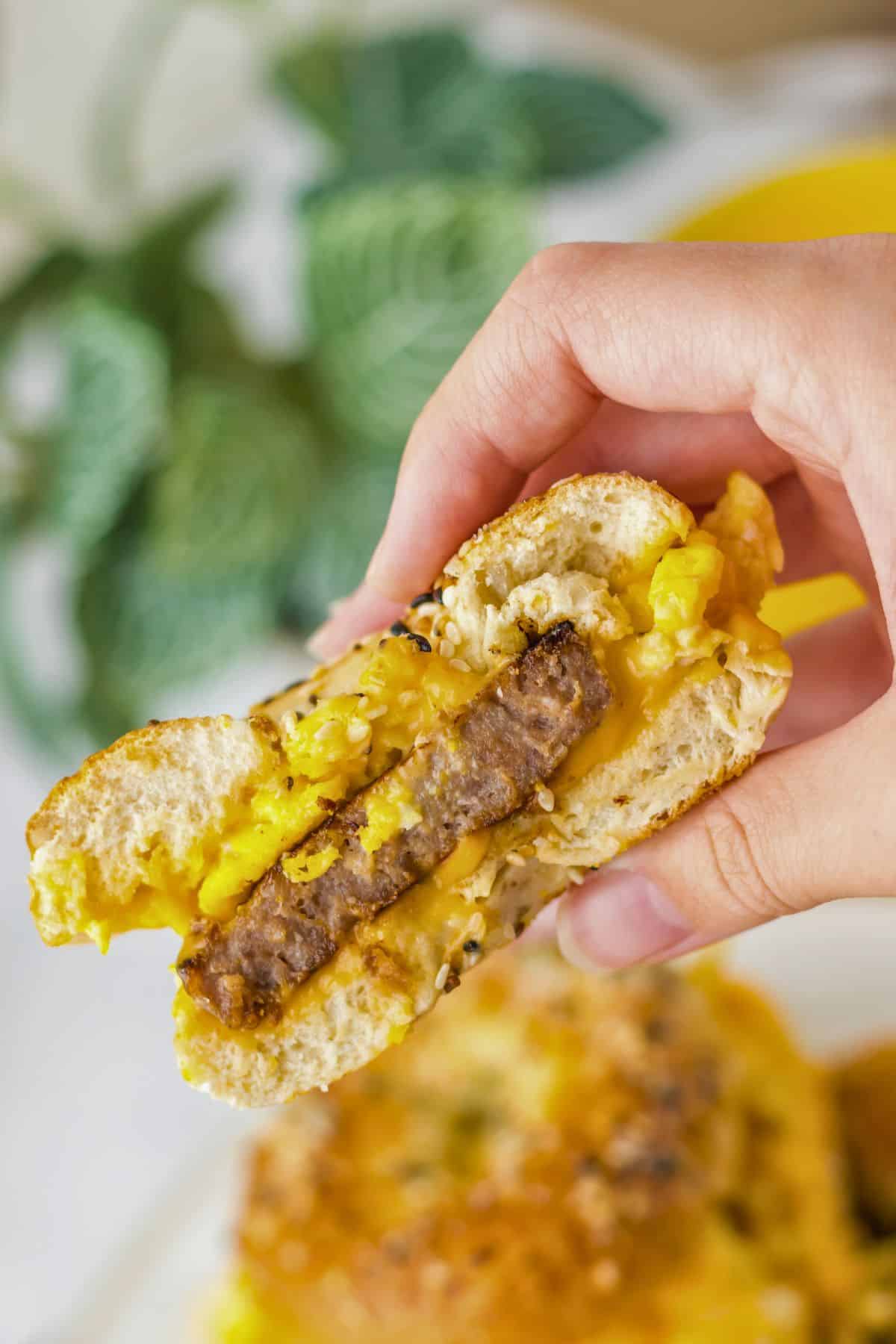 Breakfast bagel half held in a woman's hand.