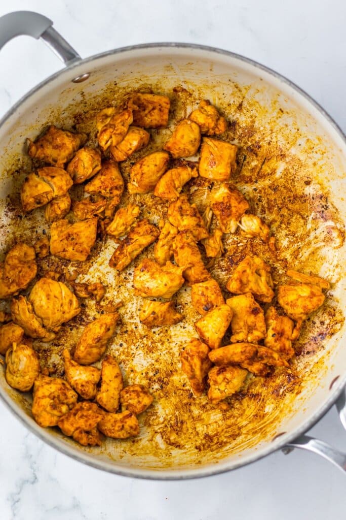 Chicken tenderloin pieces in a skillet.