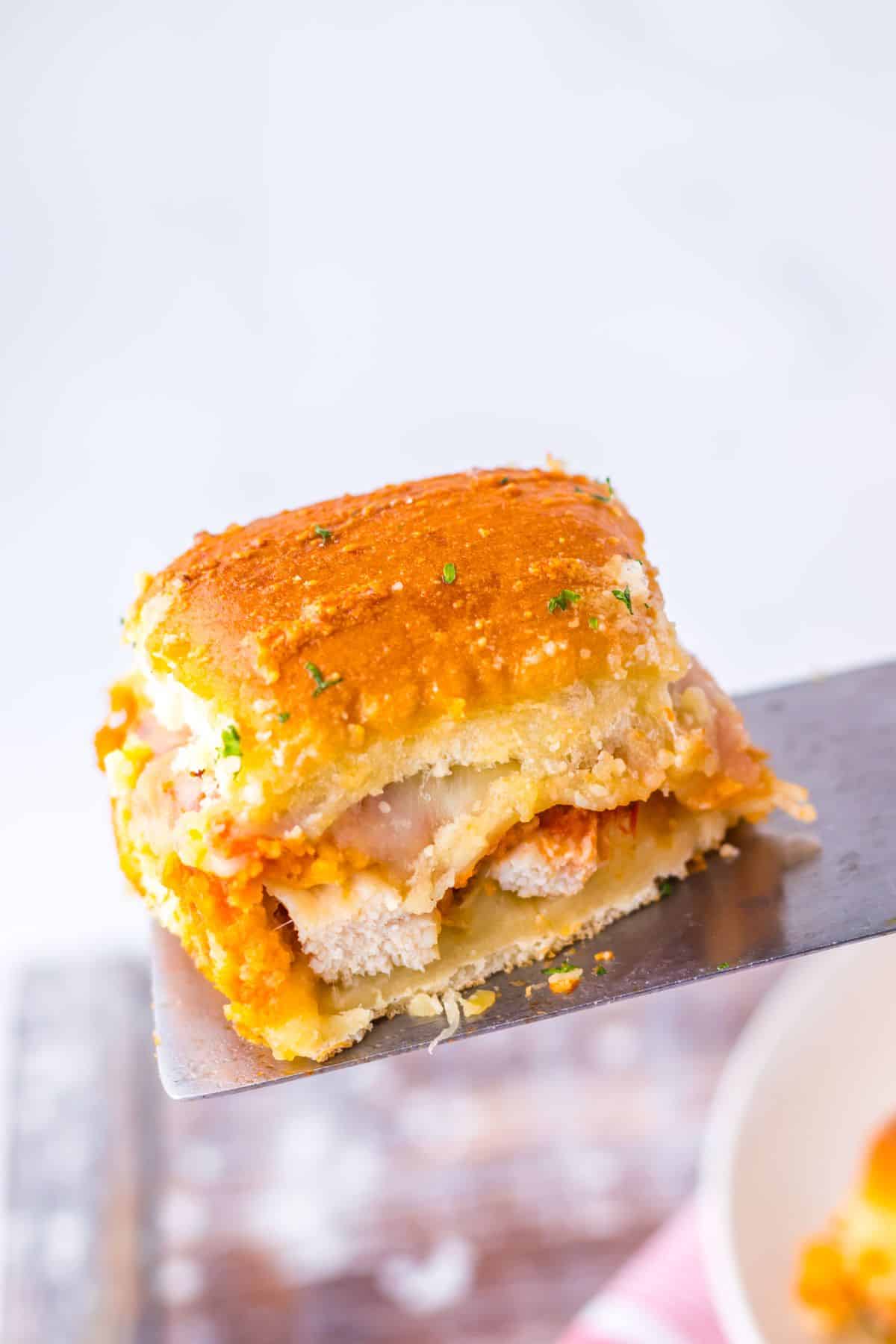 Chicken parmesan slider on a metal spatula.
