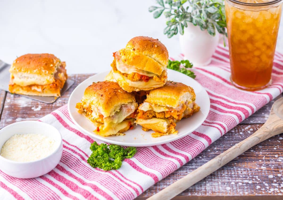 Three chicken parmesan sliders stacked on a plate.