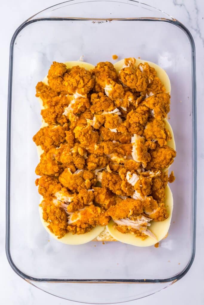 Chicken tenders being placed on rolls.