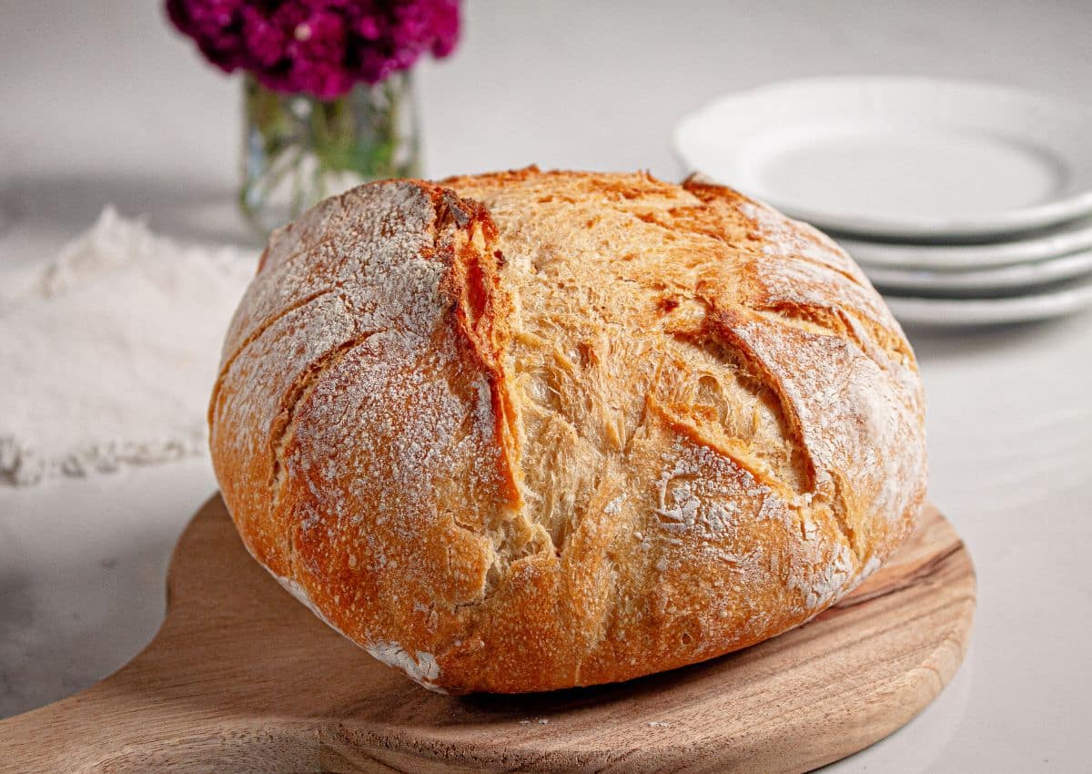 Whole loaf of sourdough bread on a wooden cutting board.