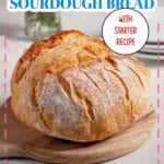 Whole sourdough bread loaf on a wooden cutting board.