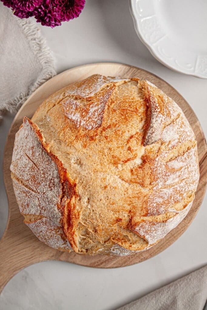 Whole loaf of sourdough bread on a wooden cutting board.