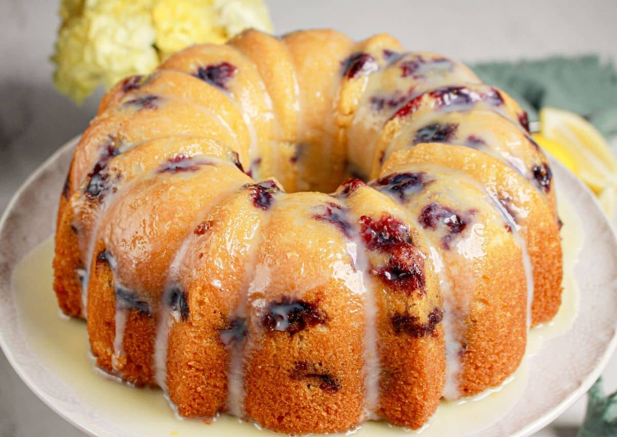 Whole lemon blueberry bundt cake on a cake stand.