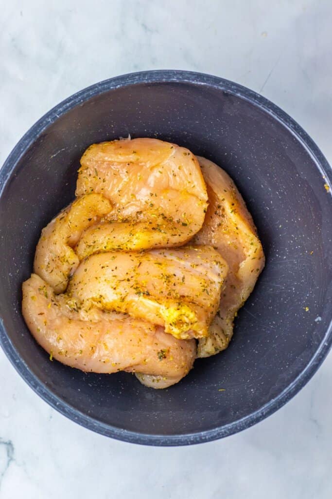 Meat being seasoned in a blue bowl.