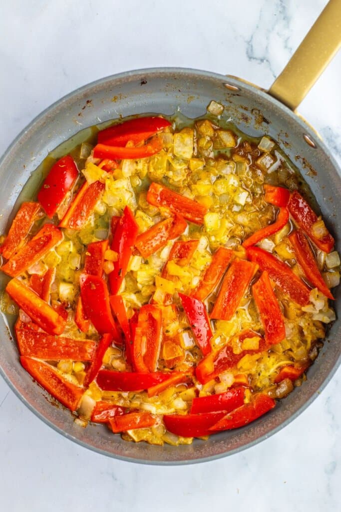 Peppers and onions being cooked in a skillet.