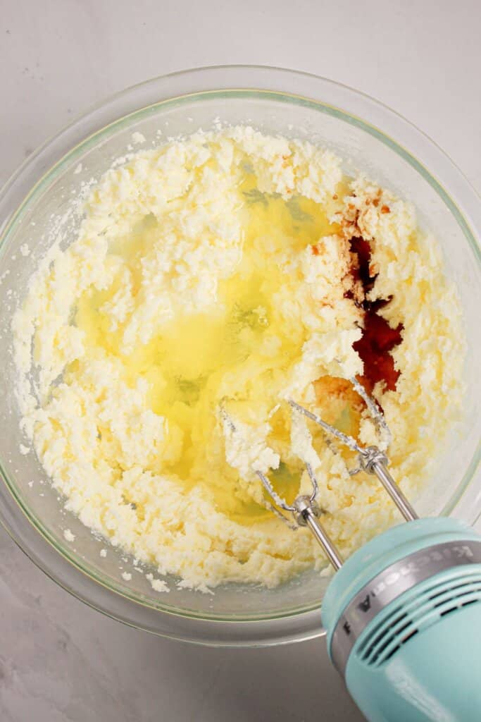 Eggs and vanilla being added to batter in a glass mixing bowl.