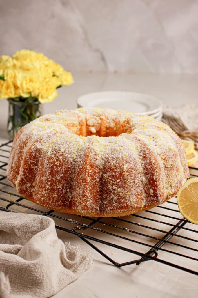 Whole lemon curd bundt cake on a wire cooling rack.