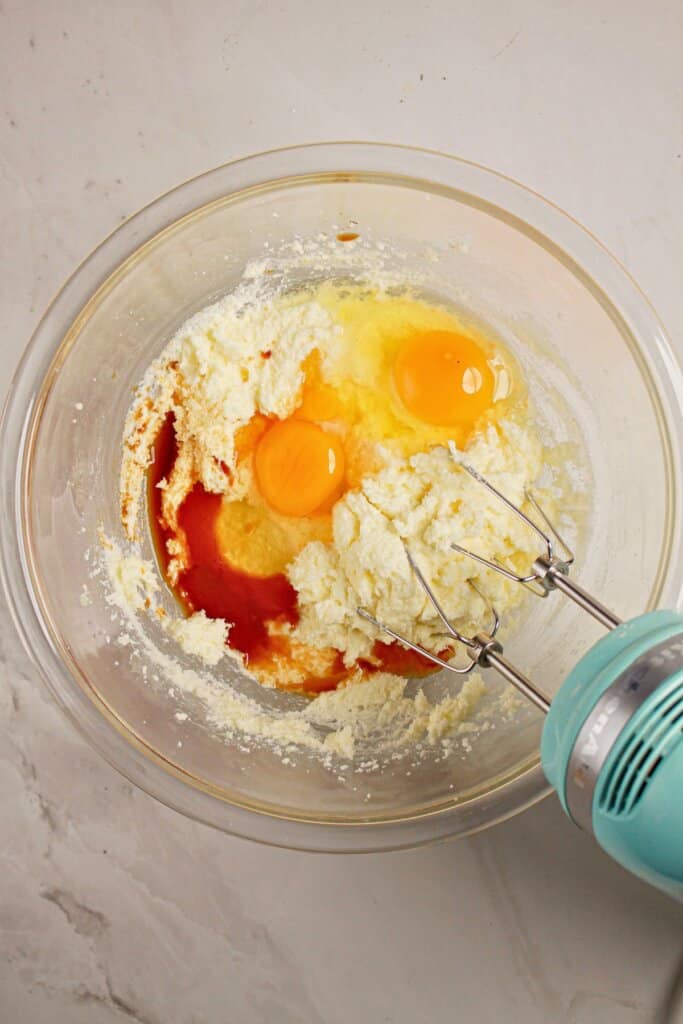 Eggs and vanilla being mixed in a glass mixing bowl.